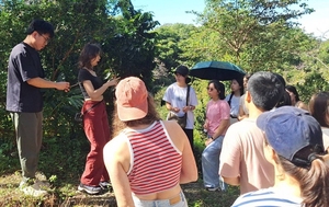 The tea farm owner explained how to observe the growth condition of tea leaves. (Photo credit: College of Foreign Languages and Literature)(Open new window/jpg file)Image