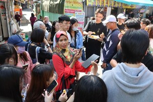 丁安妮請大家品嘗現炸點心，印尼街上的店家與客人得知有政大學生到訪，即便語言不通也熱情招待。（照片來源：社科院）(另開新視窗/jpg檔)圖片
